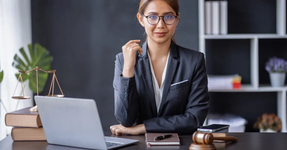 Professional female attorney at desk with laptop and law books
