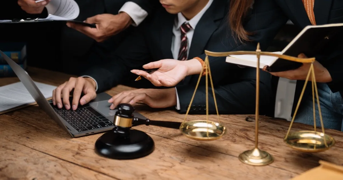 Two attorneys reviewing legal documents at a desk with gavel