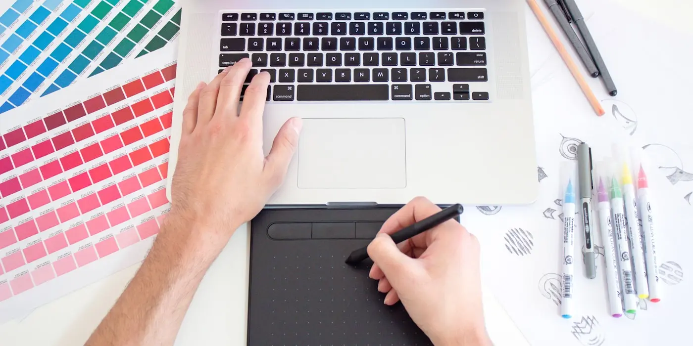 A designer working on a layout with a drawing tablet and colour swatches
